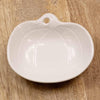 White ceramic pumpkin-shaped bowl on a wooden surface