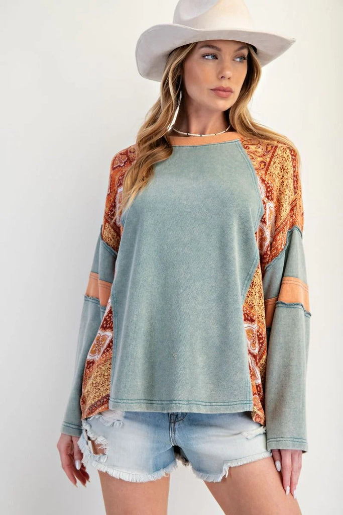 Teal mineral-washed oversized cotton jersey top with exposed seams, ribbed neckline, slightly flared sleeves, and bandana-style patchwork print on sleeves and side panels