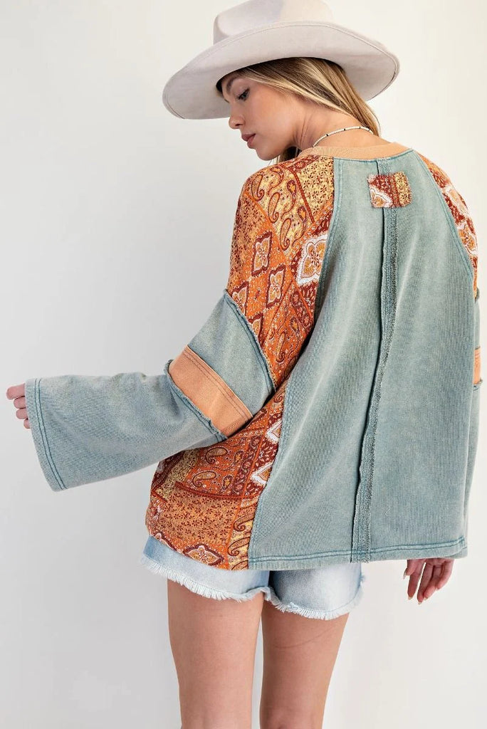 Teal mineral-washed oversized cotton jersey top with exposed seams, ribbed neckline, slightly flared sleeves, and bandana-style patchwork print on sleeves and side panels