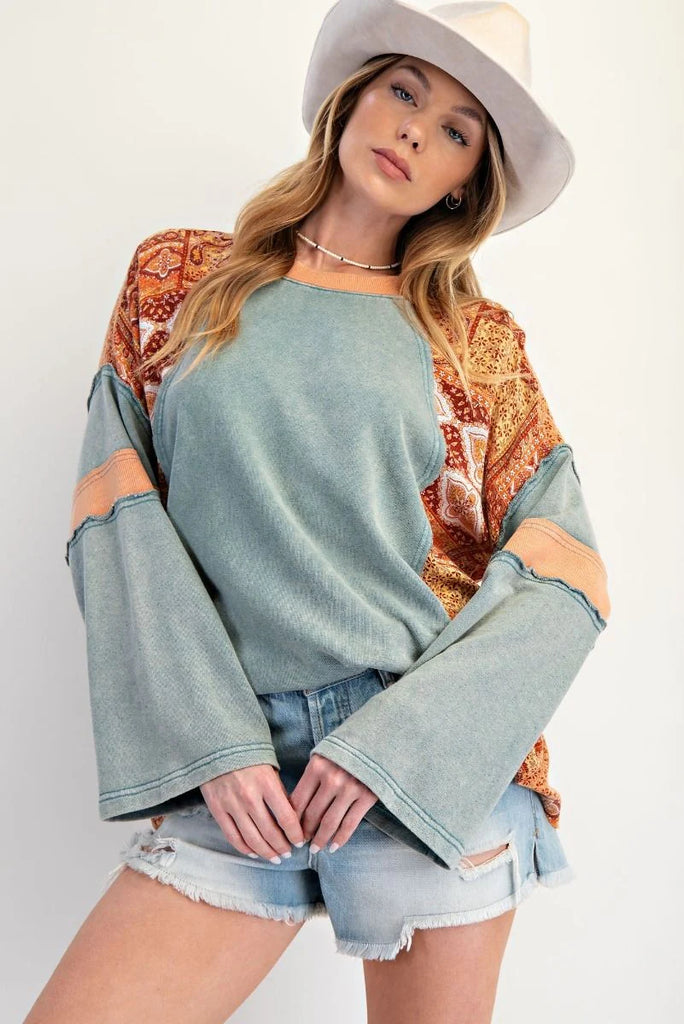 Teal mineral-washed oversized cotton jersey top with exposed seams, ribbed neckline, slightly flared sleeves, and bandana-style patchwork print on sleeves and side panels