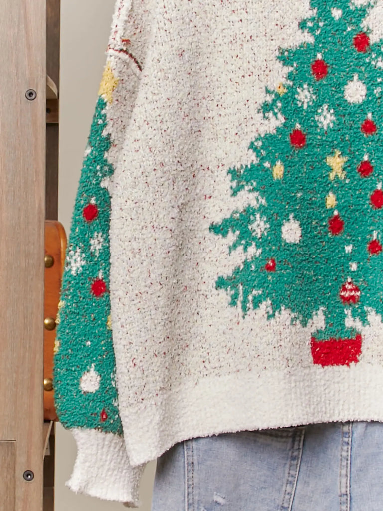 A fuzzy white knit cardigan with a green Christmas tree, red ornament, and yellow star pattern. It has a V-neckline, long sleeves, and a button-up front.