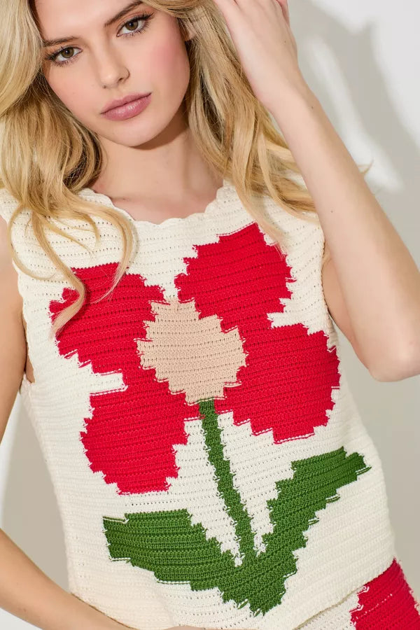 Woman wearing a sleeveless crochet top with a red flower design.