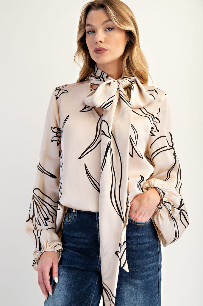 Champagne crinkled satin blouse with abstract print, high neck bow, and voluminous sleeves. Easel women's boutique
