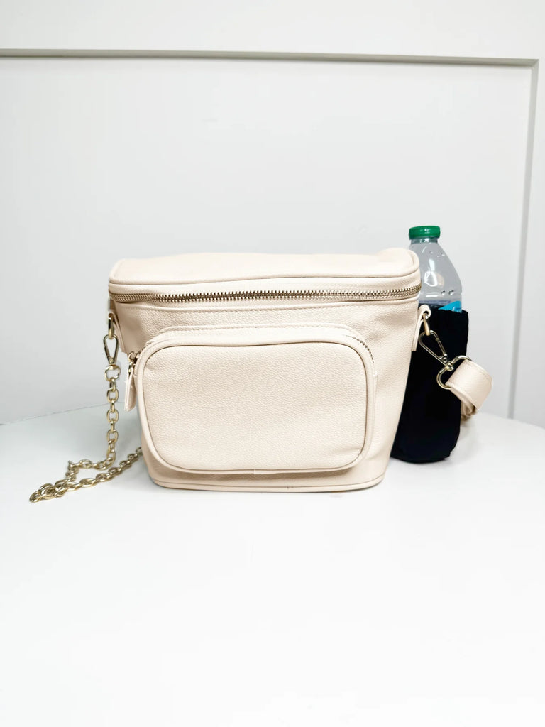 Beige crossbody bag with a chain detail on a white surface.