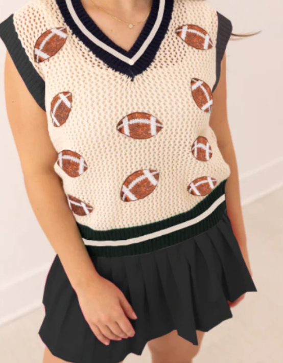Person wearing a sleeveless sweater with football patterns and a black skirt.