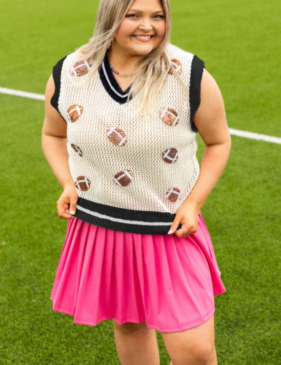 Person wearing a patterned sleeveless top and pink skirt on a grassy field