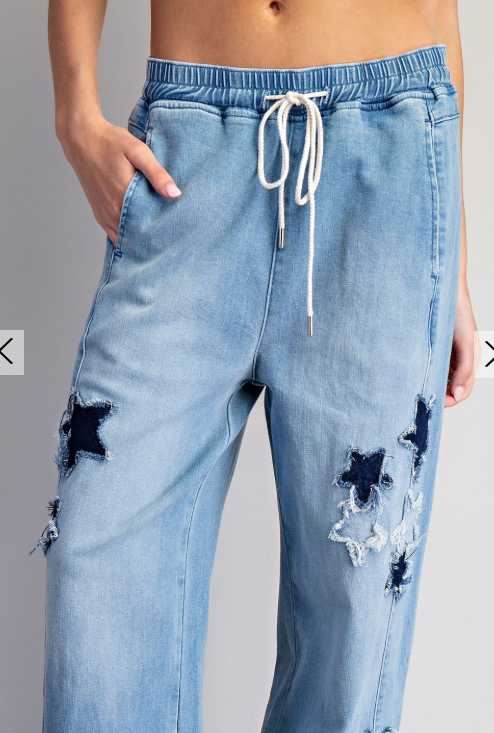 Light blue distressed jeans with a drawstring on a gray background