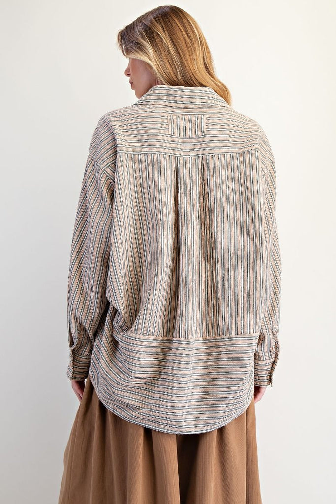 A mocha-colored, oversized button-down shirt with white and blue vertical stripes. The shirt has a classic collar, long sleeves, and a high-low hem.