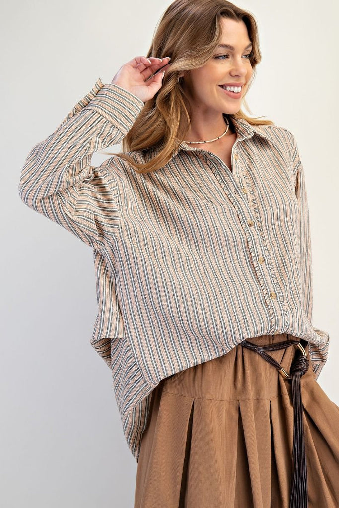 A mocha-colored, oversized button-down shirt with white and blue vertical stripes. The shirt has a classic collar, long sleeves, and a high-low hem.