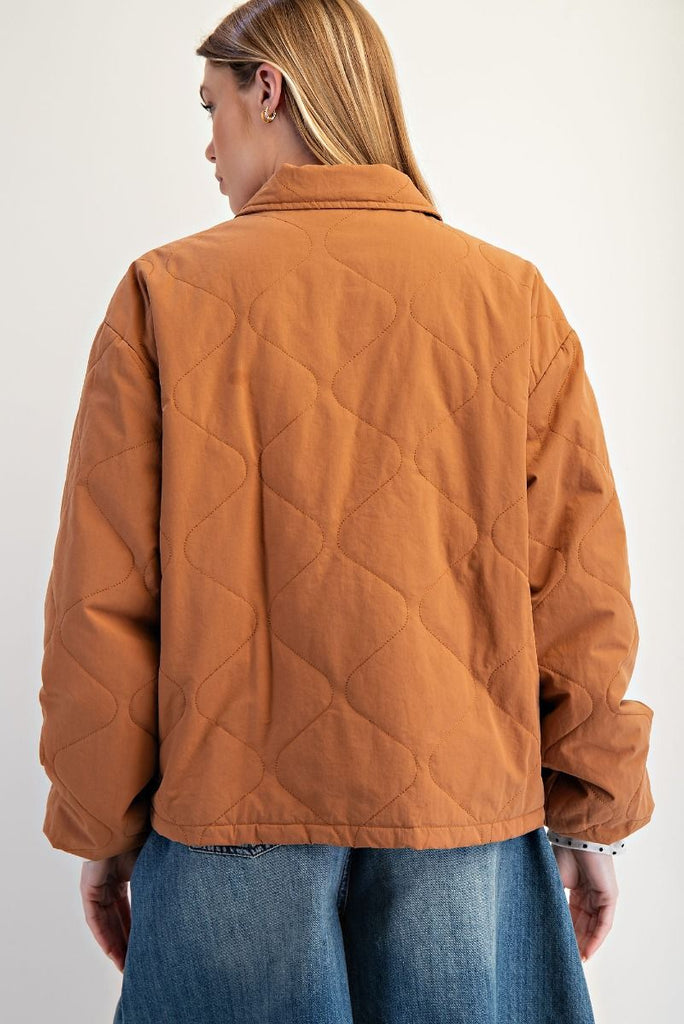 A camel-colored quilted jacket with a three-bow front closure, a collar, and elastic cuffs with a white polka dot pattern.