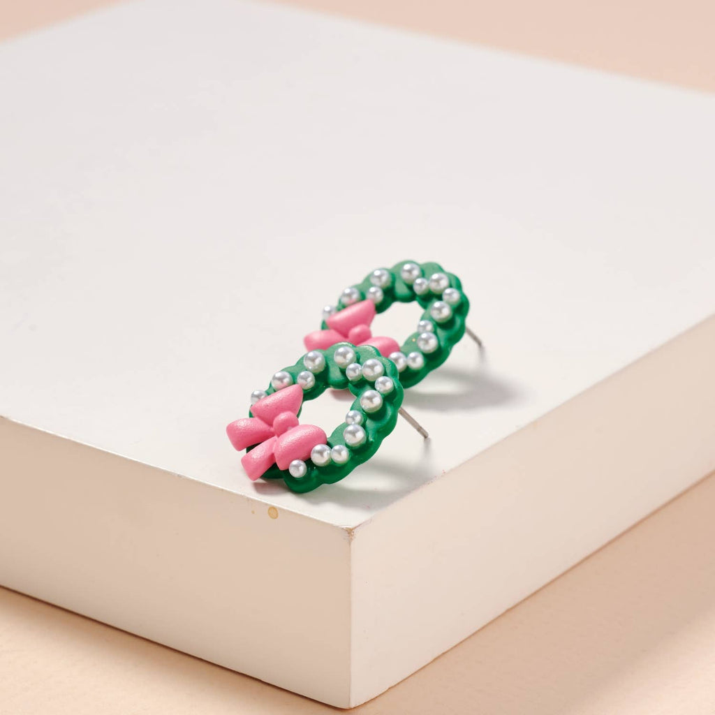 Green enamel Christmas wreath stud earrings with pearl accents and pink bows.