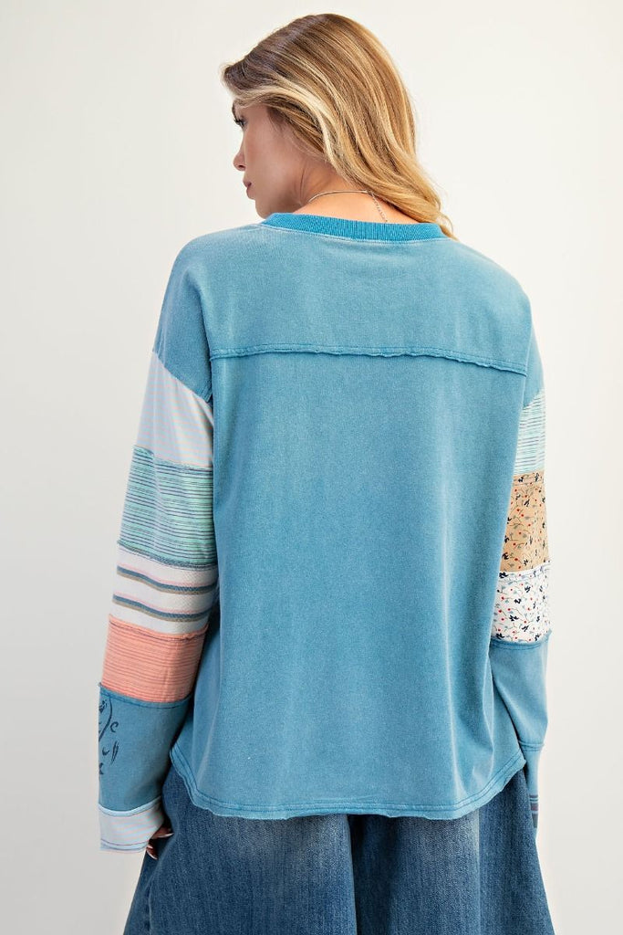 A faded teal, soft-washed terry pullover. It has a crew neck and a chest panel with horizontal stripes. The sleeves have a patchwork design of mixed stripes and floral fabrics.