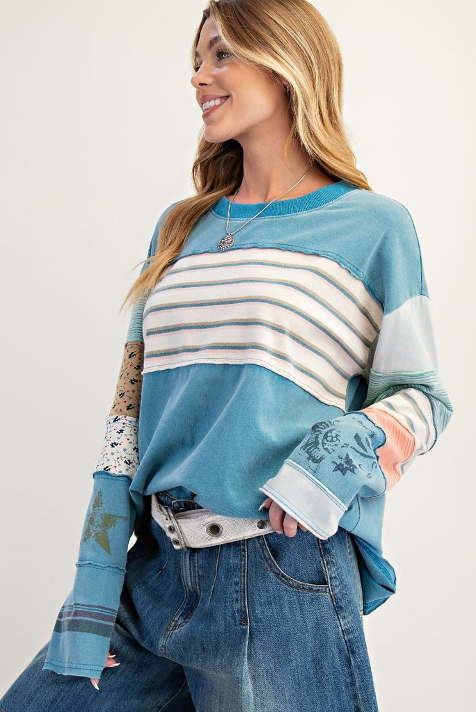 A faded teal, soft-washed terry pullover. It has a crew neck and a chest panel with horizontal stripes. The sleeves have a patchwork design of mixed stripes and floral fabrics.