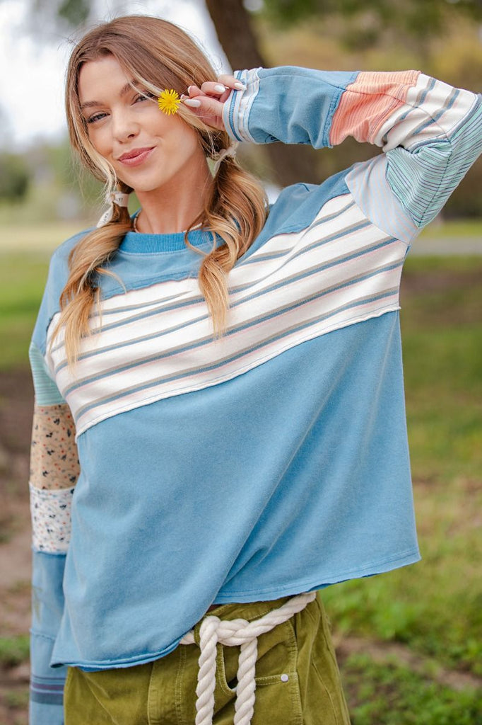 A faded teal, soft-washed terry pullover. It has a crew neck and a chest panel with horizontal stripes. The sleeves have a patchwork design of mixed stripes and floral fabrics.