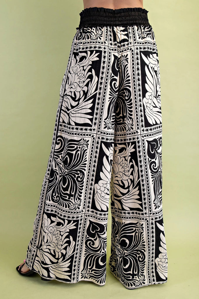 Black and white patterned wide-leg pants on a green background