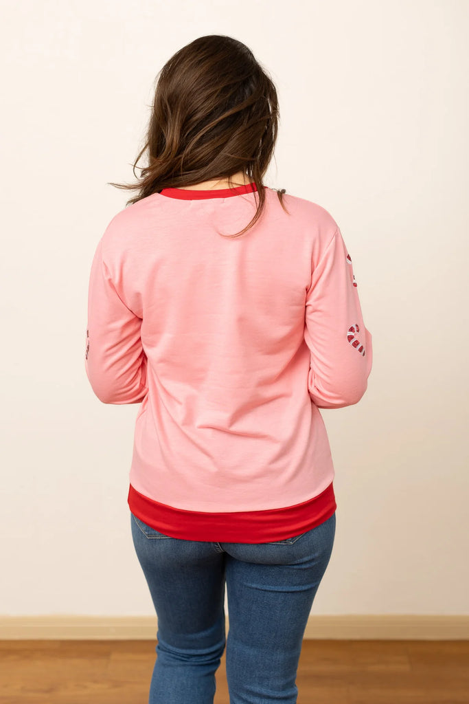 Tella Jolly But Twisted sweatshirt in pastel pink with a red sequin graphic and ribbed collar and cuffs, shown with a relaxed fit for a festive and fun look