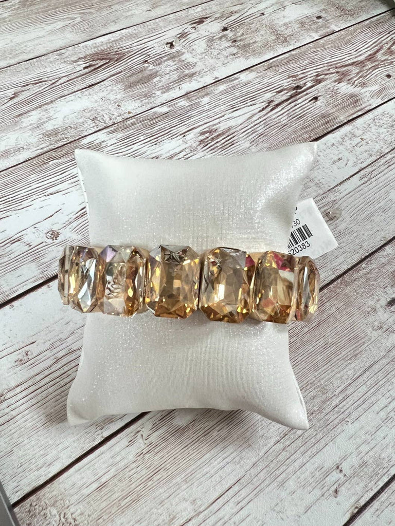 Gold-toned stretch bracelet with large faceted topaz-colored stones displayed on a white pillow.