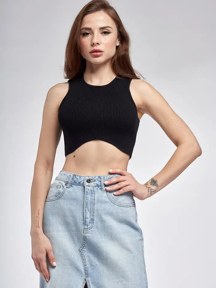 A woman stands facing forward, wearing a fitted, ribbed black crop top with a rounded hemline that dips at the center. She pairs it with high-waisted jeams.