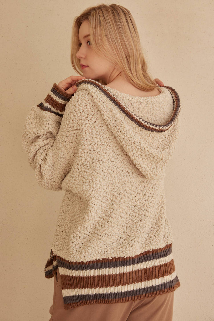 Cream hooded puff sweater with brown striped trim and kangaroo pocket.