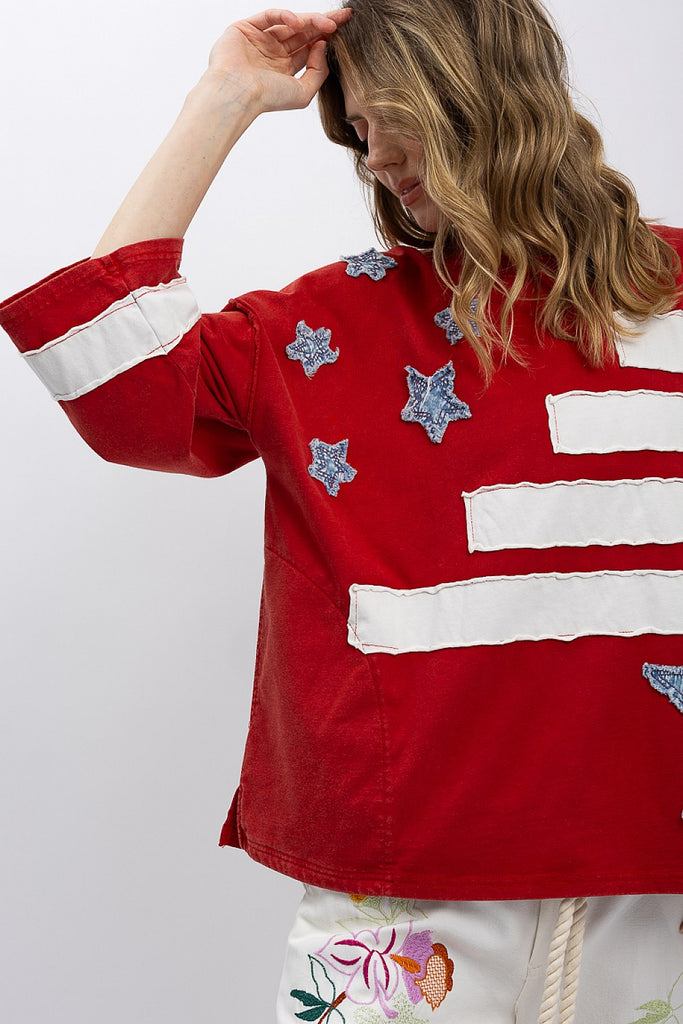 Show your spirit in the Zelia Patchwork Flag T-Shirt. This oversized, distressed red top features a cool, raw-edge flag design. Ships fast from North Missouri!