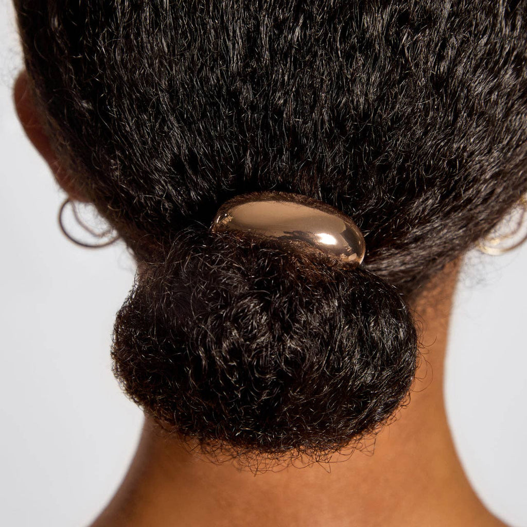 Close-up of a person's hair bun with a hair tie against a white background