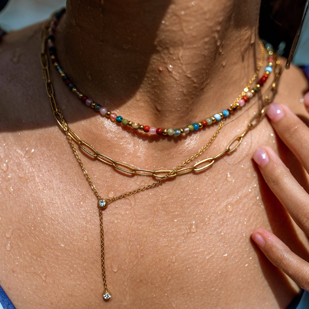 Close-up of a person wearing multiple necklaces on a sunlit background