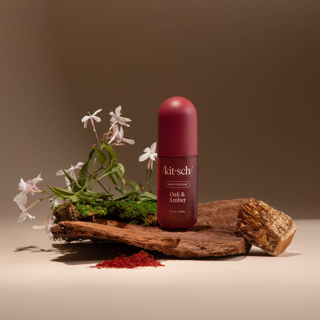 Kit-sch bottle of Oak & Amber on a wooden platform with flowers and natural elements.