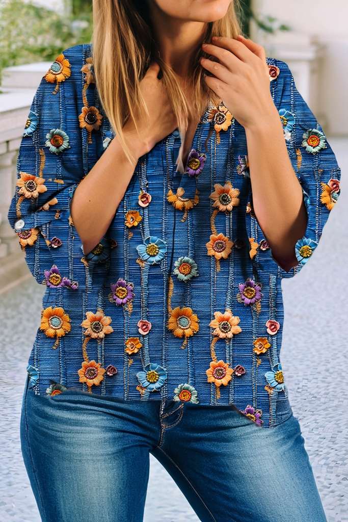 Woman wearing a blue floral V-neck blouse with roll-up sleeves, styled casually with denim.