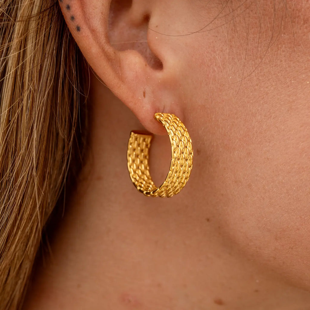 Gold hoop earring worn by a person with blonde hair.
