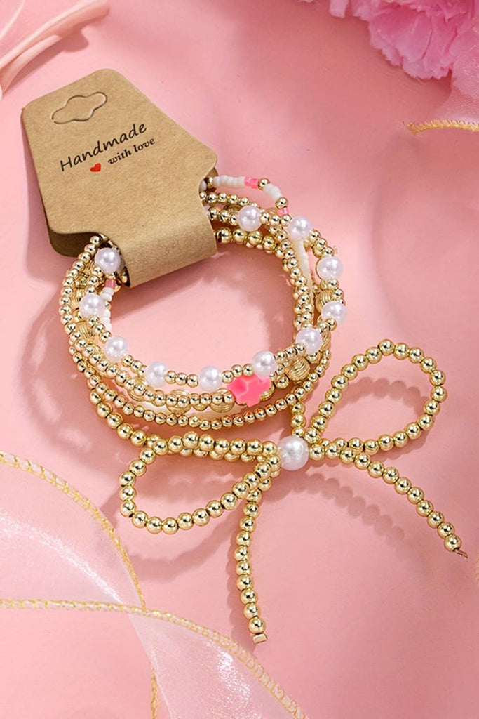 “Gold bow knot layered bracelet with faux pearl beads and multiple strands, boutique women’s jewelry accessory for casual or dressy looks.”