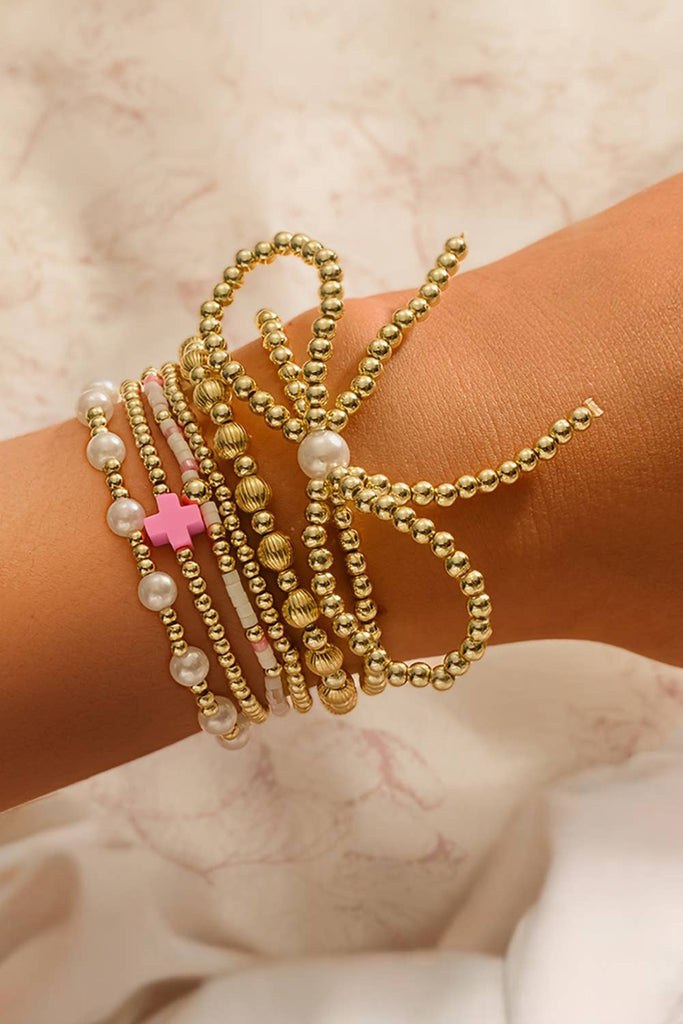 “Gold bow knot layered bracelet with faux pearl beads and multiple strands, boutique women’s jewelry accessory for casual or dressy looks.”
