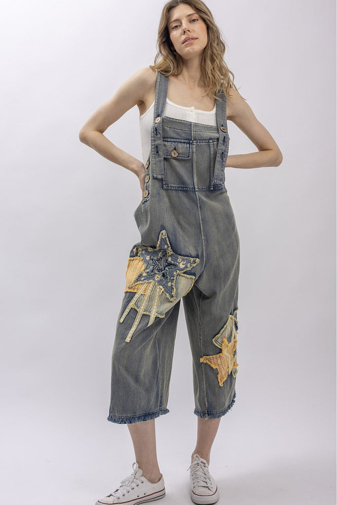 Woman wearing denim overalls with star designs on a white background