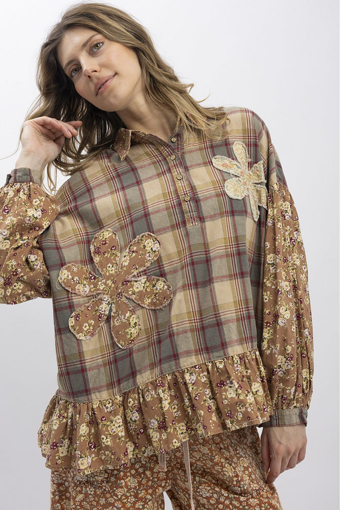 Woman wearing a plaid shirt with floral embellishments on a white background