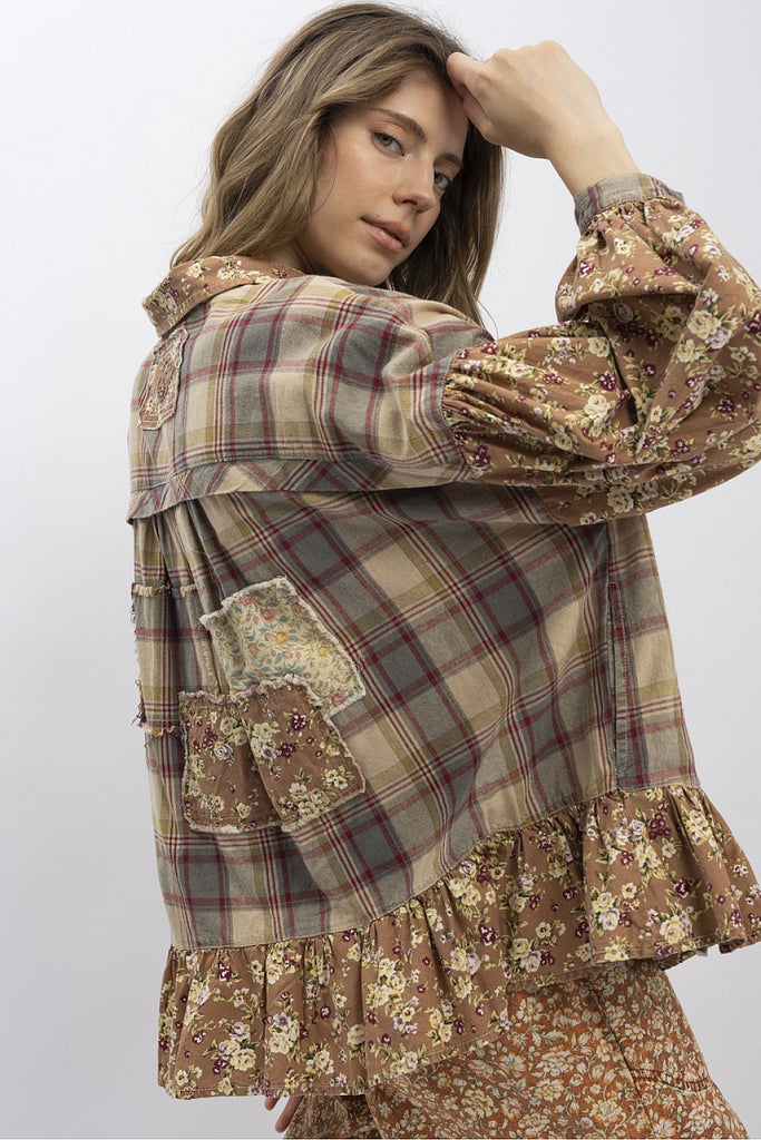 Woman wearing floral patchwork plaid top with ruffle hem and bubble sleeves in earthy tones.