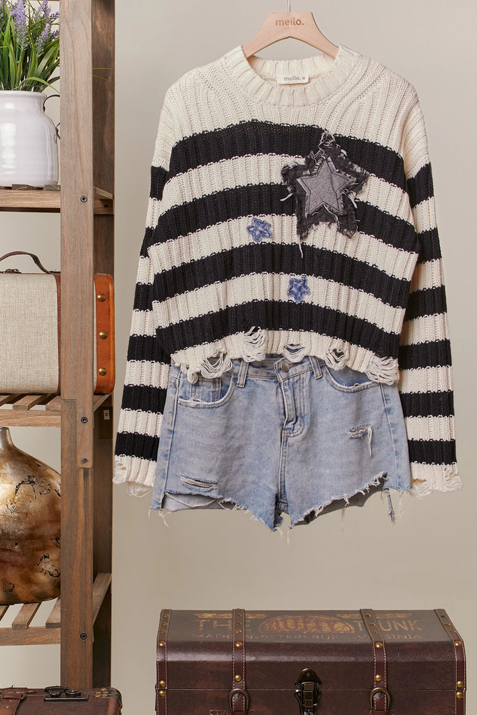 Black and cream striped distressed sweater with star patch and frayed hemline, cropped fit.