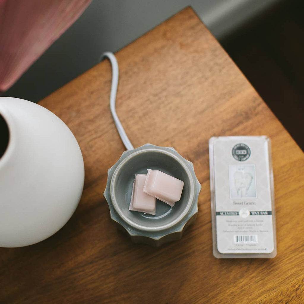 White diffuser, gray container with pink cubes, and a package on a wooden surface