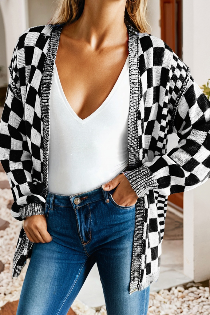 Person wearing a black and white checkered cardigan over a white top and blue jeans.