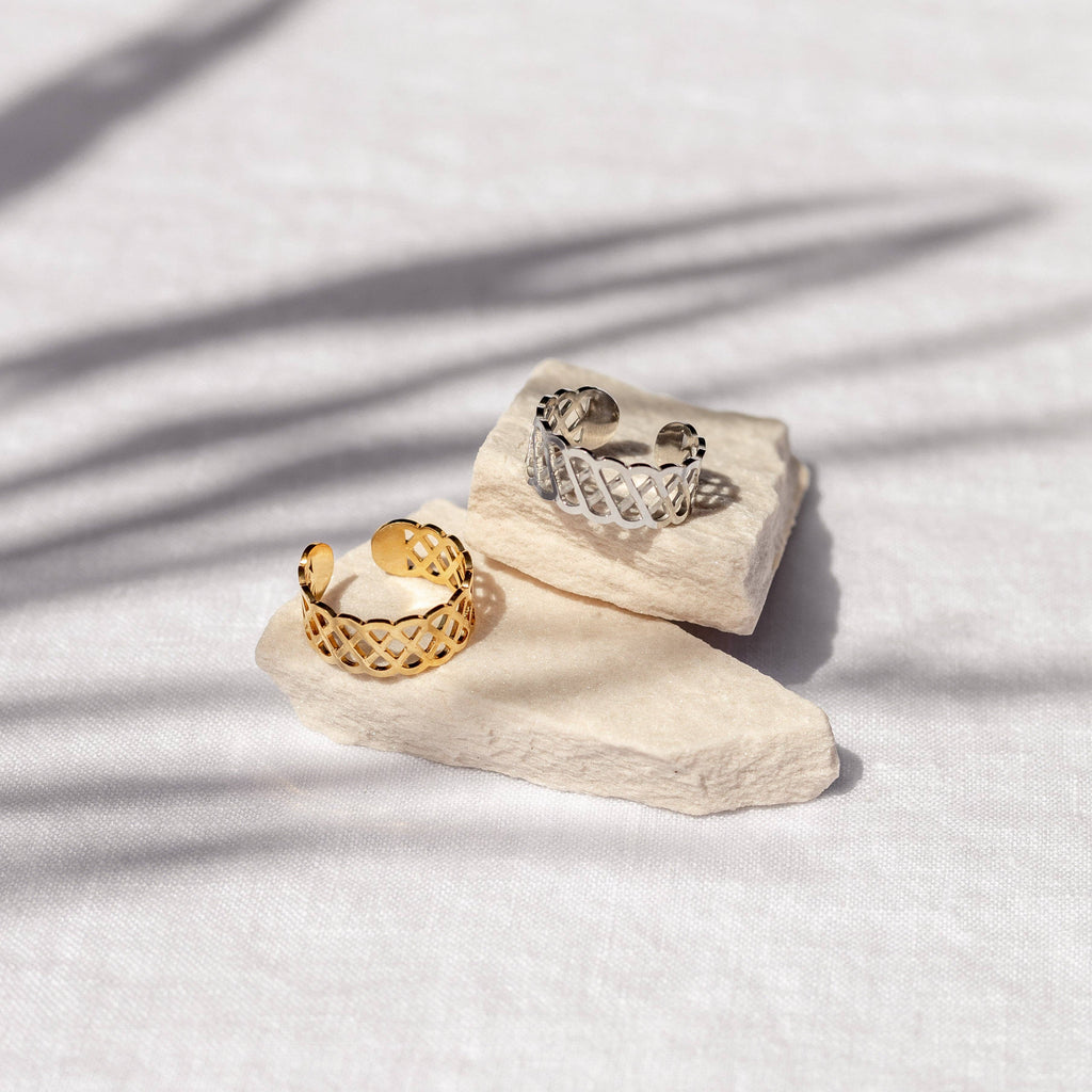 Two gold and silver rings on a textured white surface with soft shadows.