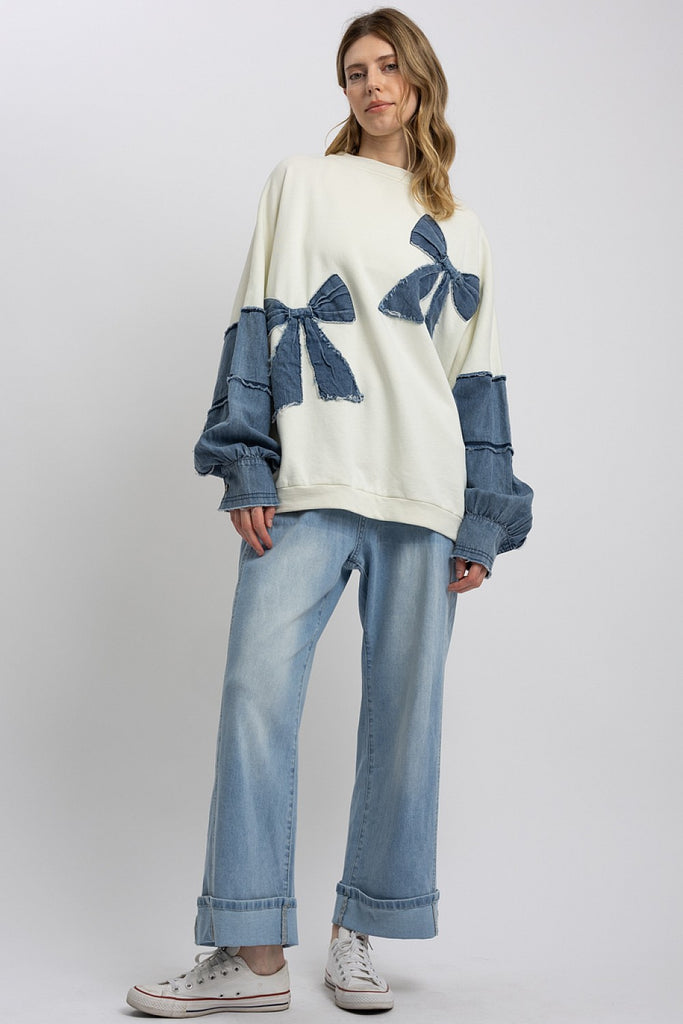 Marceline Denim Bow Contrast Sweatshirt featuring oversized fit, frayed denim bows, and soft mineral-washed French terry fabric.