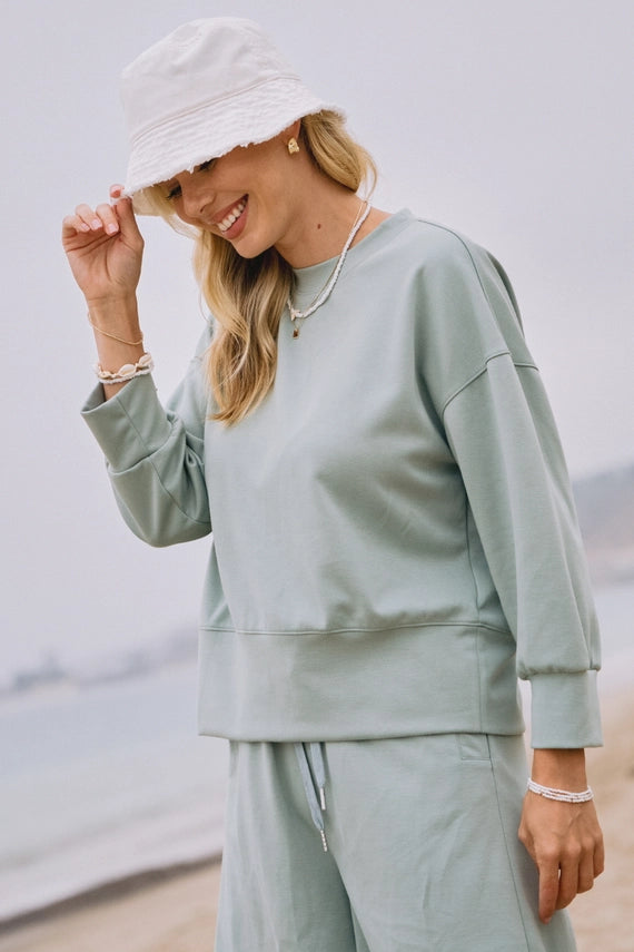 Woman in light green outfit with bucket hat on a beach