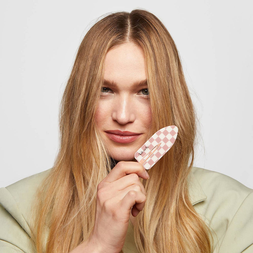 Woman holding a checkered comb against a plain background