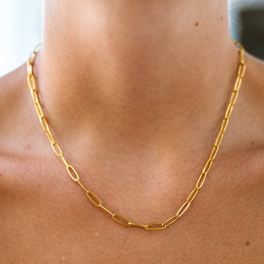 Gold chain necklace on a person's neck with a blurred background