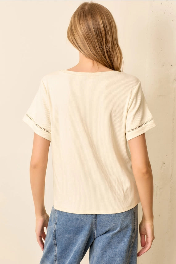 Person wearing a beige t-shirt with white trim on a plain background