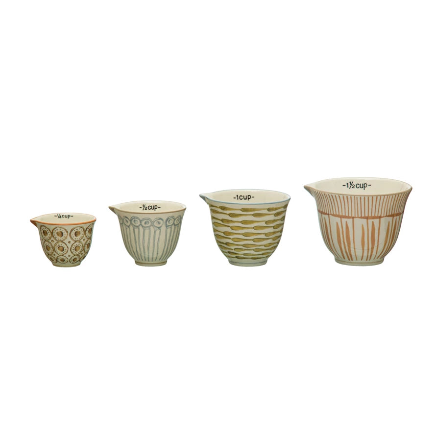 Set of four ceramic measuring cups with different markings on a white background
