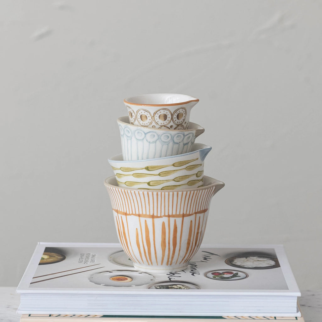 Stack of ceramic bowls with patterns on a magazine against a gray background