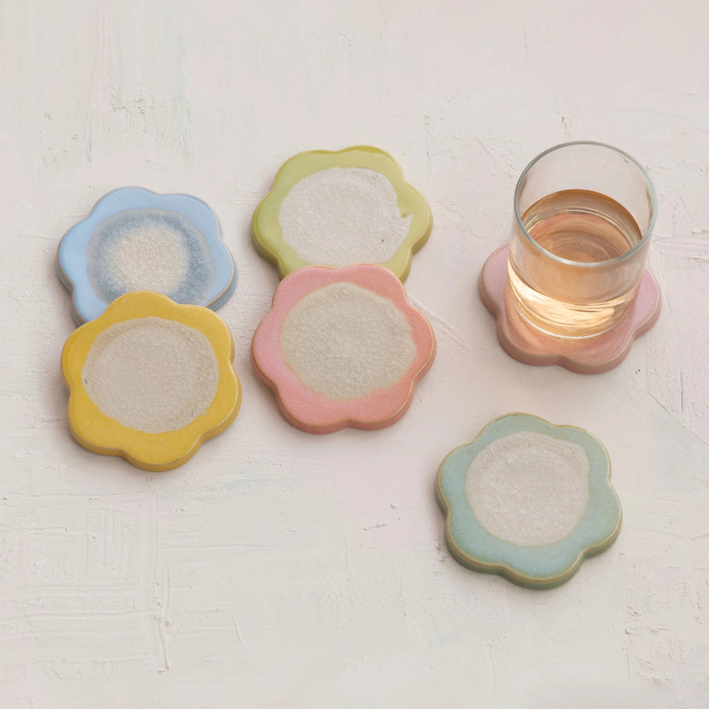 Set of colorful ceramic coasters on a light surface with a glass of water.