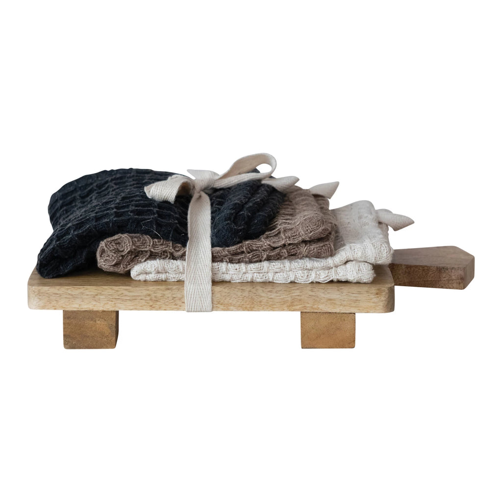Stack of folded clothes on a wooden tray with a white background