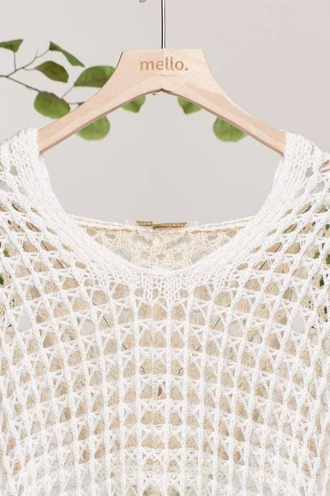 White crochet top on a hanger with 'mello' branding against a light background.
