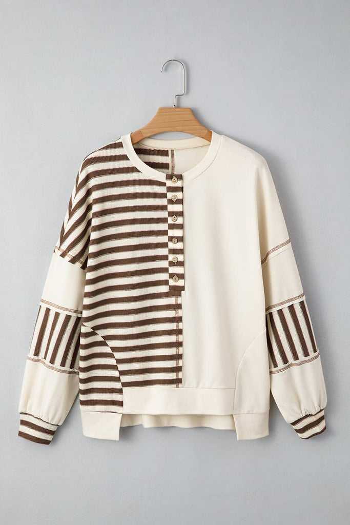 Striped sweater on a hanger against a gray background