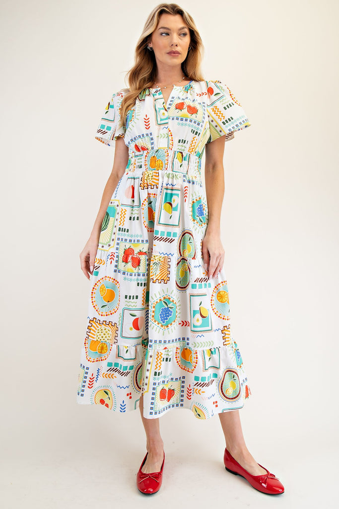 White midi dress with colorful fruit print, tiered skirt, ruched waist, and notched neckline. women's boutique easel
